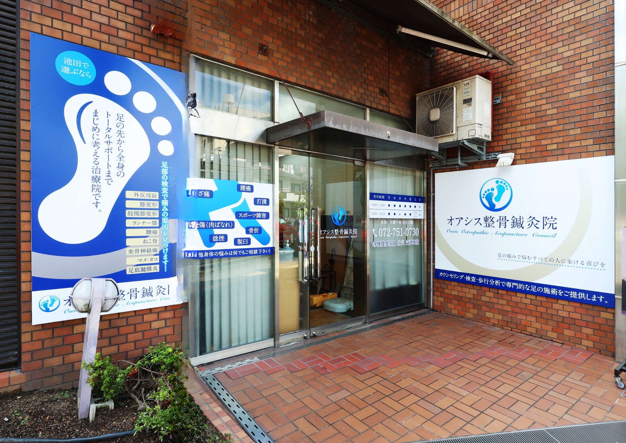 オアシス整骨鍼灸院の外観。入口左側の青い足型看板が目印です