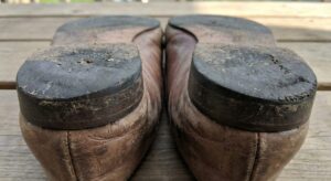 踵の内側が極端にすり減った靴底。足首が内側に倒れ込む過回内（オーバープロネーション）のサインを示すリアルな摩耗状態。