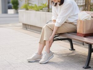 旅行や買い物のあとにベンチで足を休める女性