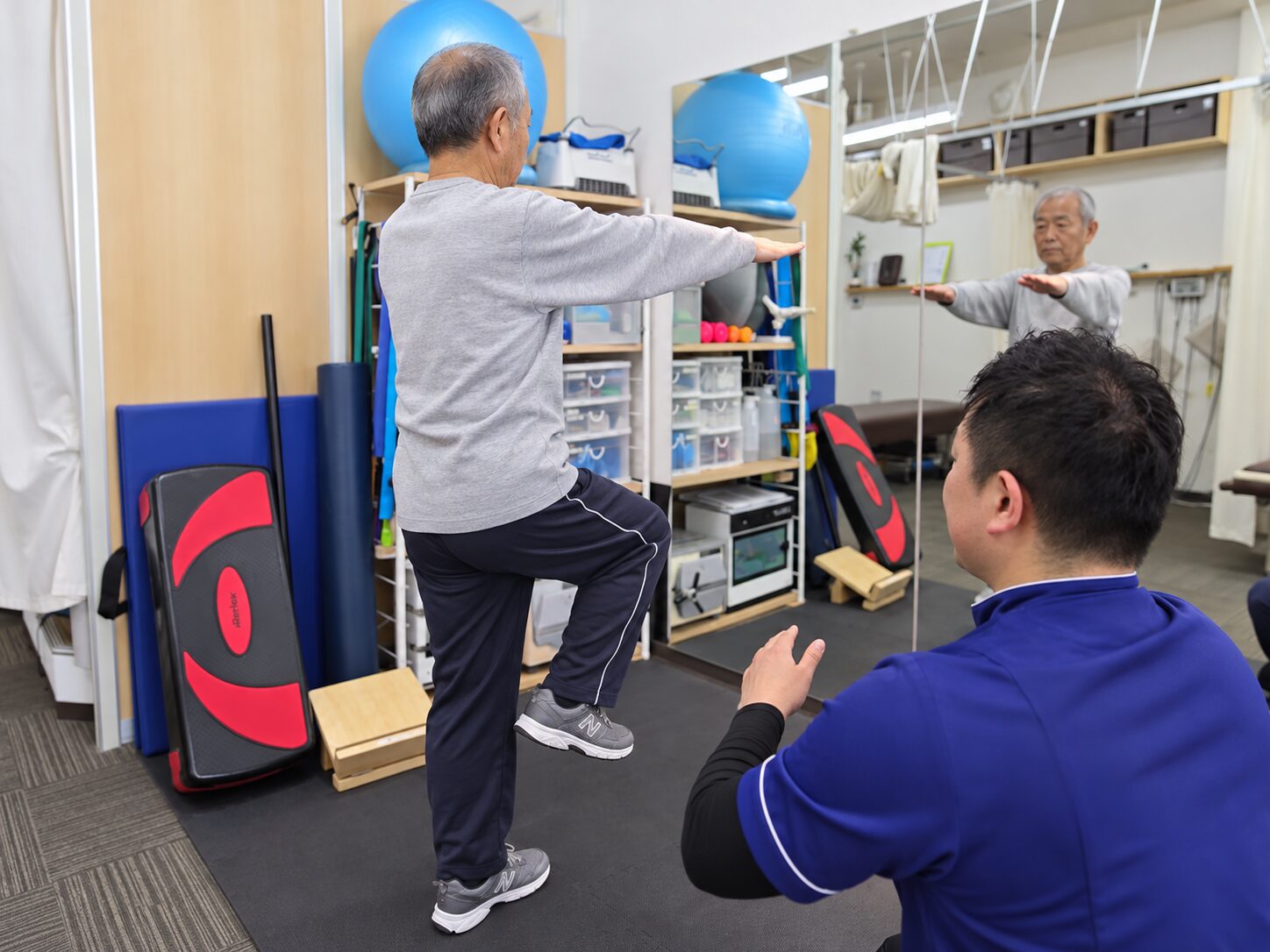 鏡を使い、片脚立位で骨盤を安定させる運動練習の再現イメージ